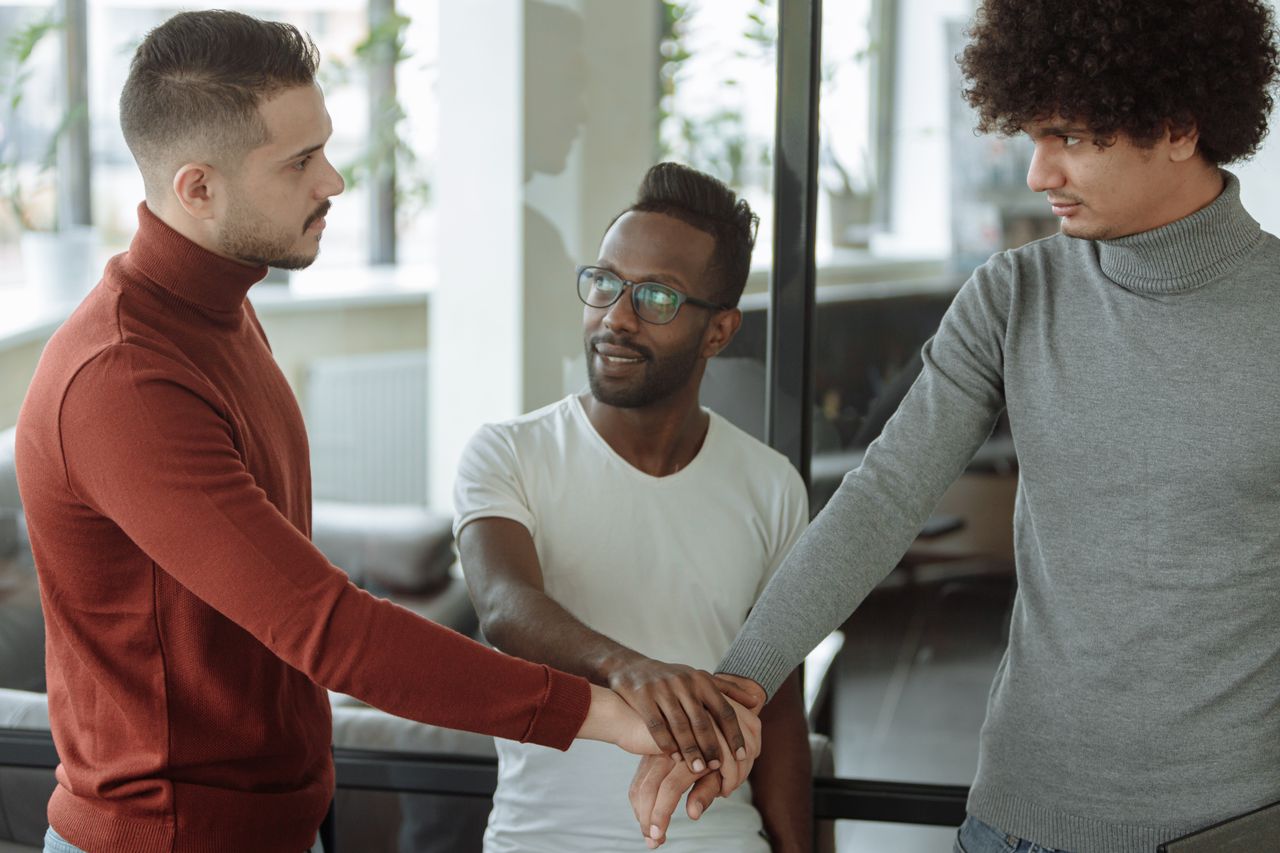 Services Three diverse men collaborate, showcasing teamwork and unity in an office setting.